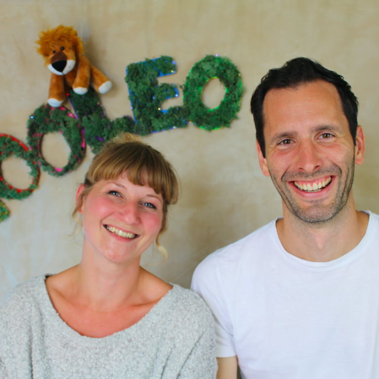 Gianna und Simon sind das Gründer-Team von YOOLEO. Sie sitzen nebeneinander und lächeln