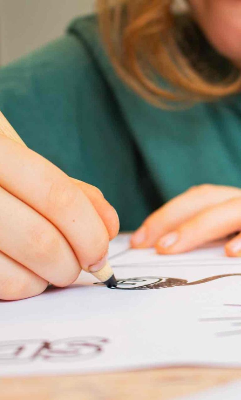 Eine Person zeichnet mit einem Stift auf weißem Papier.